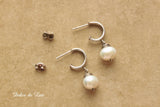 White freshwater pearls on silver hoop stud earrings.